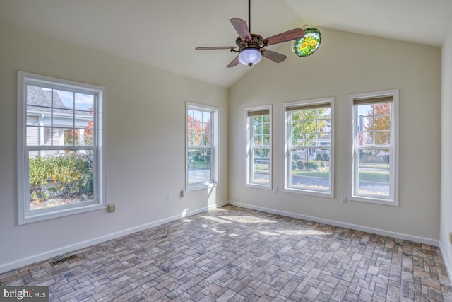 empty room featuring vaulted ceiling, a healthy amount of sunlight, and ceiling fan