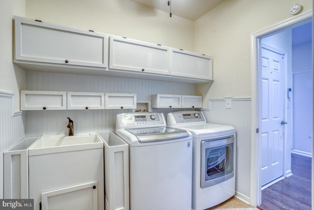 laundry area featuring washer and dryer, cabinets, and light hardwood / wood-style floors