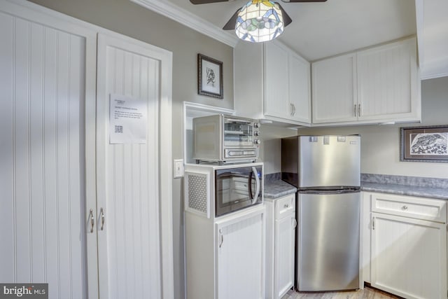 kitchen with ceiling fan, crown molding, stainless steel refrigerator, and white cabinets