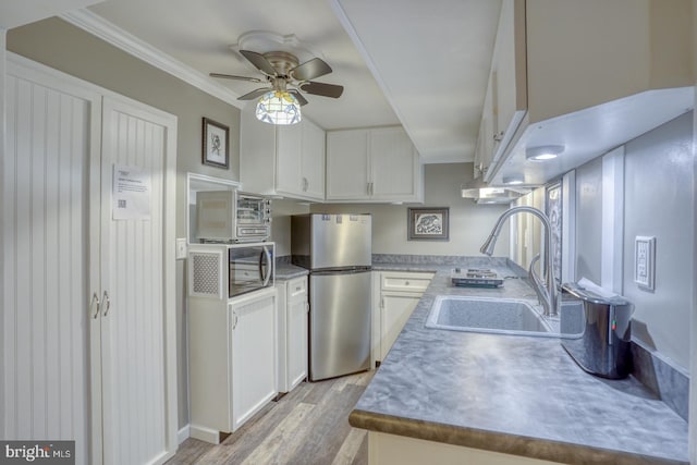 kitchen with sink, appliances with stainless steel finishes, light hardwood / wood-style flooring, and white cabinets