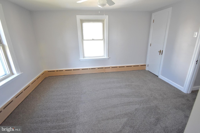 carpeted spare room with a baseboard radiator and ceiling fan