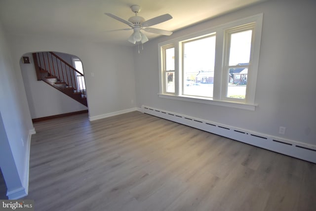 unfurnished room featuring ceiling fan, a baseboard heating unit, and hardwood / wood-style floors