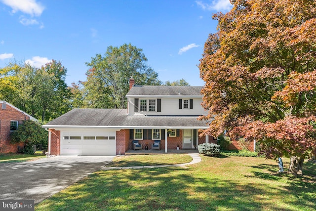 view of front of house featuring a front yard, covered porch, and a garage