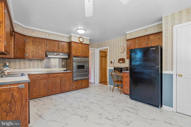 kitchen with oven, sink, stovetop, and black fridge