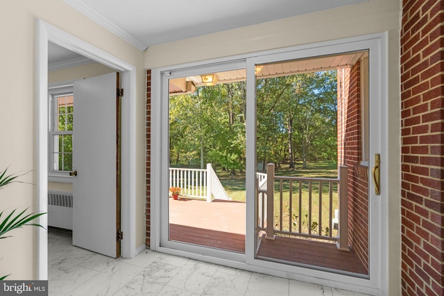 entryway featuring ornamental molding, radiator heating unit, brick wall, and a wealth of natural light