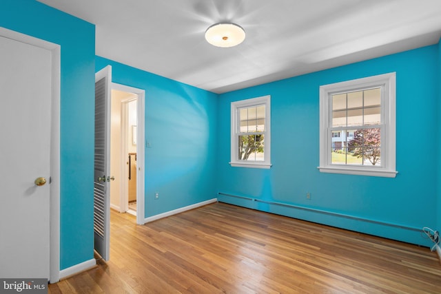 empty room with baseboard heating and hardwood / wood-style floors