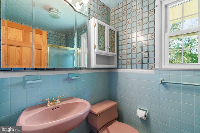 bathroom featuring toilet, sink, and tile walls