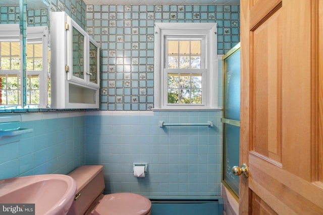 full bathroom featuring sink, toilet, tile walls, and shower / bath combination with glass door