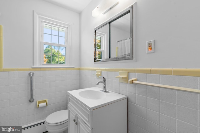 bathroom with vanity, toilet, tile walls, and a baseboard heating unit