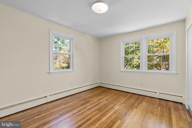 unfurnished room featuring light hardwood / wood-style floors, baseboard heating, and plenty of natural light