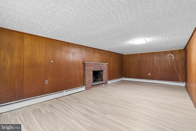 unfurnished living room with light hardwood / wood-style floors, a textured ceiling, and a baseboard heating unit