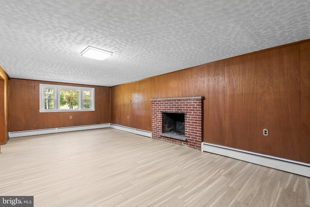 unfurnished living room featuring a fireplace, a textured ceiling, a baseboard heating unit, and light wood-type flooring