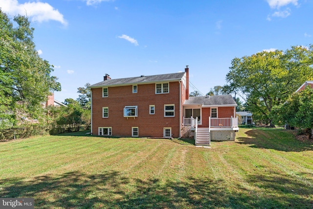 rear view of property featuring a deck and a lawn