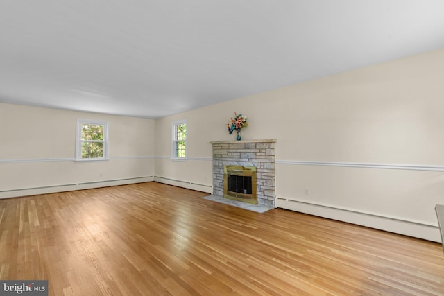 unfurnished living room featuring a stone fireplace, light hardwood / wood-style flooring, and baseboard heating