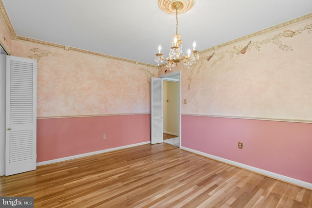 unfurnished room featuring ornamental molding, a chandelier, and hardwood / wood-style flooring