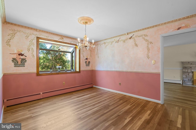 unfurnished room featuring baseboard heating, hardwood / wood-style floors, a notable chandelier, and a stone fireplace