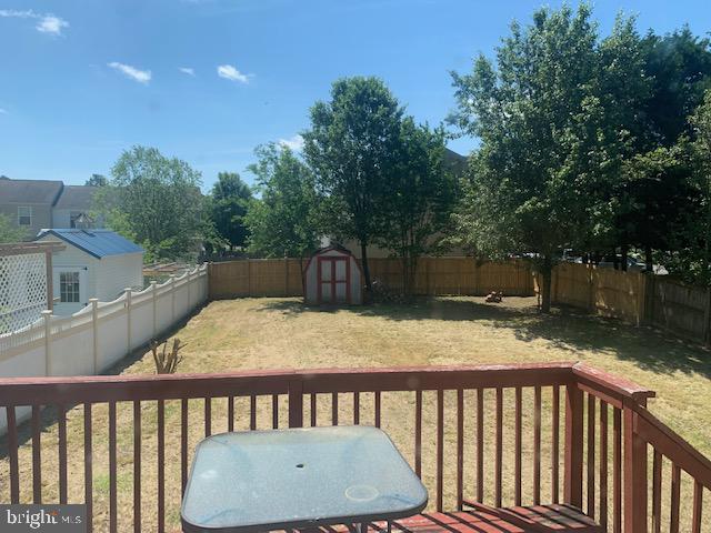 wooden terrace with a storage shed and a lawn