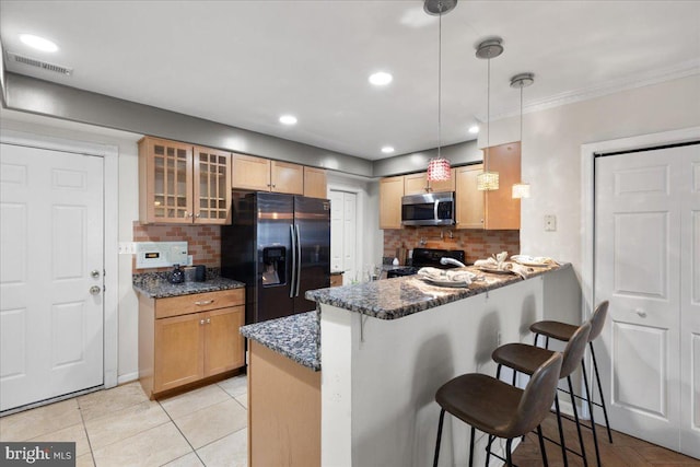 kitchen with black appliances, kitchen peninsula, dark stone counters, decorative light fixtures, and a breakfast bar