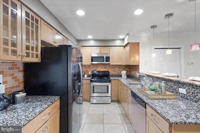 kitchen featuring tasteful backsplash, appliances with stainless steel finishes, sink, dark stone counters, and pendant lighting