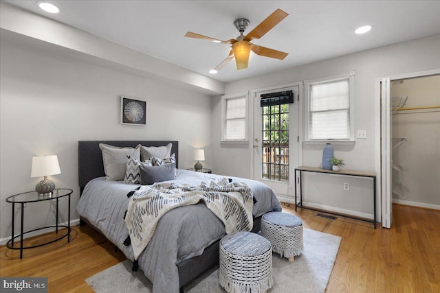 bedroom featuring access to outside, a spacious closet, a closet, ceiling fan, and hardwood / wood-style flooring