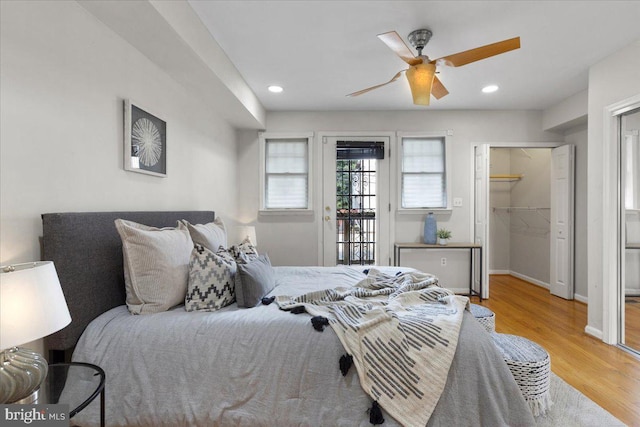 bedroom with a closet, access to outside, a walk in closet, light hardwood / wood-style floors, and ceiling fan