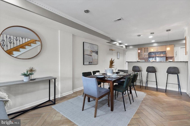 dining room with crown molding and light parquet flooring