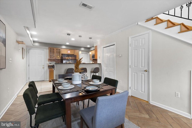 dining room with ornamental molding and light parquet flooring