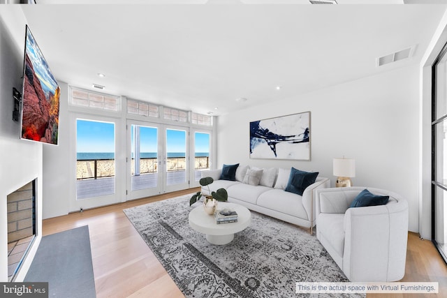 living room featuring light hardwood / wood-style flooring and a water view