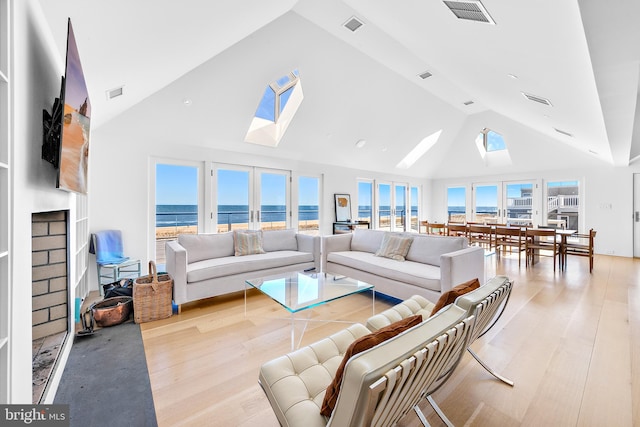 living room with plenty of natural light, high vaulted ceiling, and light hardwood / wood-style flooring