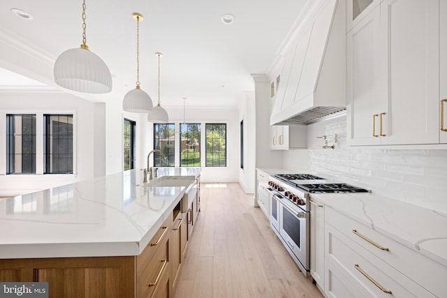 kitchen featuring range with two ovens, a spacious island, pendant lighting, white cabinets, and light stone counters