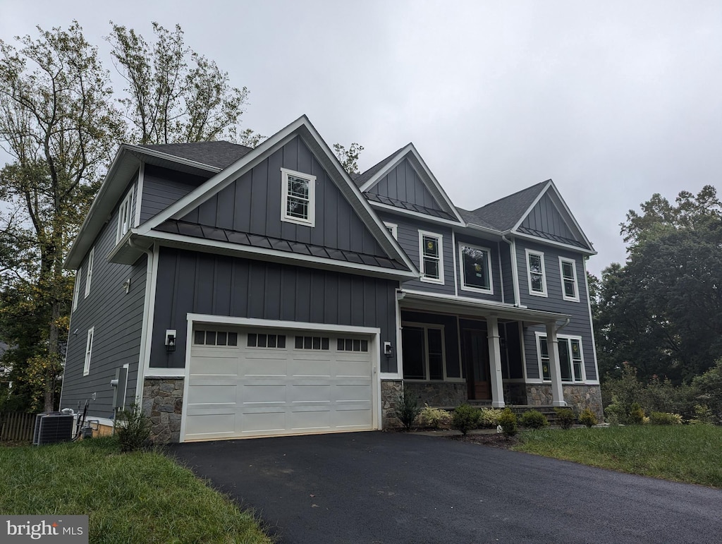 craftsman-style house with central air condition unit, covered porch, and a garage