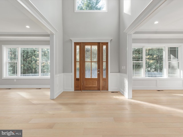 entryway with a towering ceiling, plenty of natural light, and light wood-type flooring