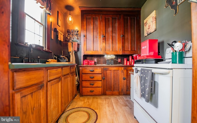 kitchen with sink, decorative backsplash, pendant lighting, and light wood-type flooring