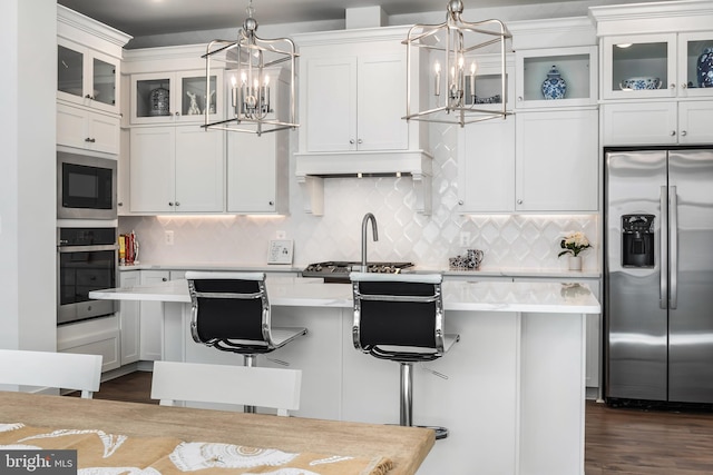 kitchen with hanging light fixtures, a kitchen island, appliances with stainless steel finishes, a breakfast bar, and white cabinetry