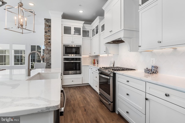 kitchen featuring dark wood-type flooring, hanging light fixtures, stainless steel appliances, sink, and white cabinets