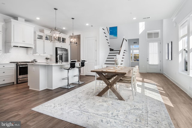 kitchen featuring appliances with stainless steel finishes, white cabinetry, hardwood / wood-style flooring, decorative backsplash, and a kitchen island with sink