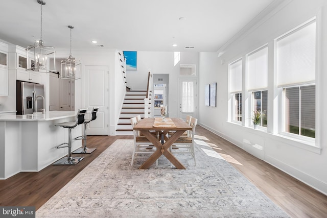 dining space featuring sink, crown molding, an inviting chandelier, and dark hardwood / wood-style floors