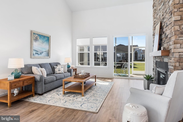 living room with light hardwood / wood-style floors, high vaulted ceiling, and a fireplace