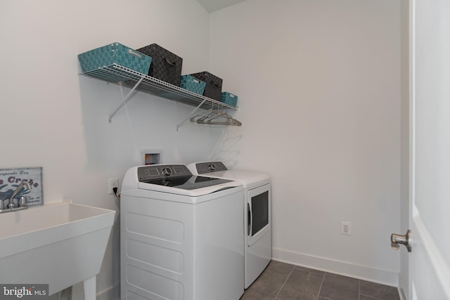 laundry area with sink, washing machine and clothes dryer, and dark tile patterned flooring