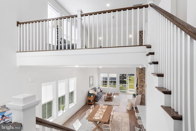 stairs with hardwood / wood-style floors and a high ceiling