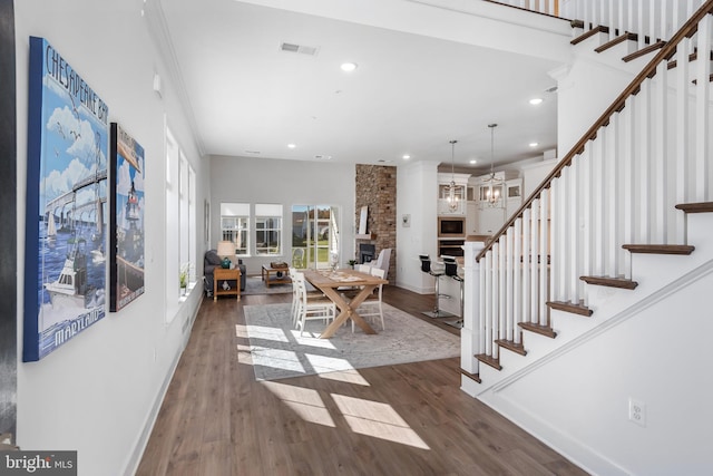 interior space featuring an inviting chandelier, dark hardwood / wood-style flooring, a fireplace, and ornamental molding