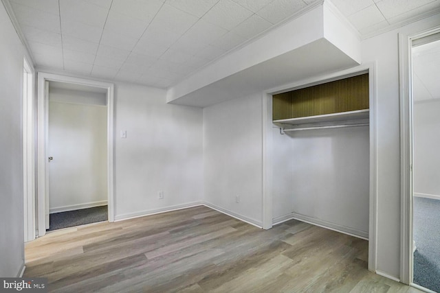 unfurnished bedroom featuring a closet, wood finished floors, and baseboards