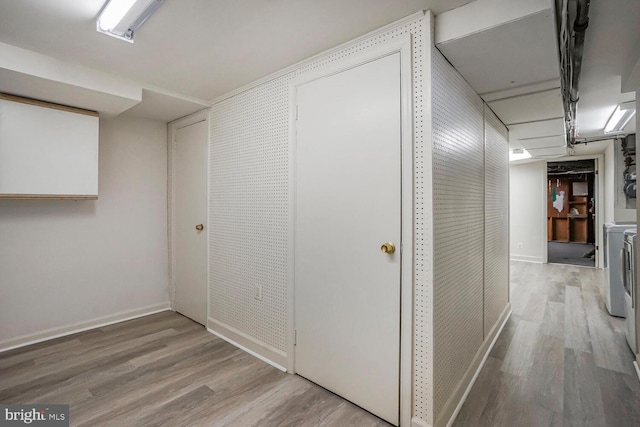 hall featuring light wood-type flooring, baseboards, and washing machine and clothes dryer