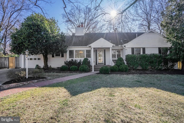 view of front of property featuring a front yard, fence, a chimney, and an attached garage