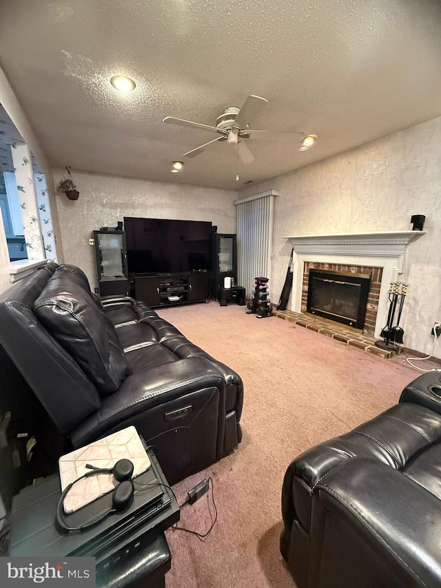 carpeted cinema room with ceiling fan, a fireplace, and a textured ceiling