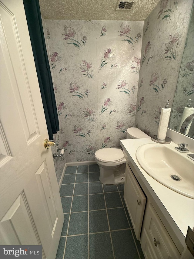 bathroom featuring vanity, toilet, and a textured ceiling