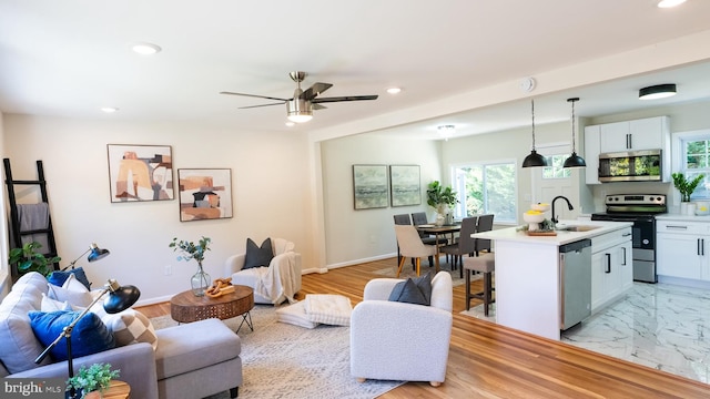 living room with sink, light hardwood / wood-style floors, and ceiling fan