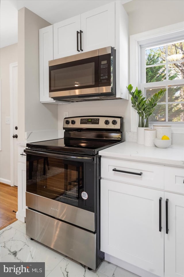 kitchen with appliances with stainless steel finishes, light hardwood / wood-style flooring, and white cabinetry