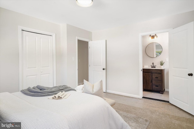 carpeted bedroom featuring connected bathroom, sink, and a closet