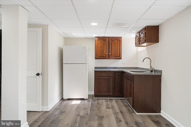 kitchen featuring a paneled ceiling, hardwood / wood-style flooring, sink, and white refrigerator